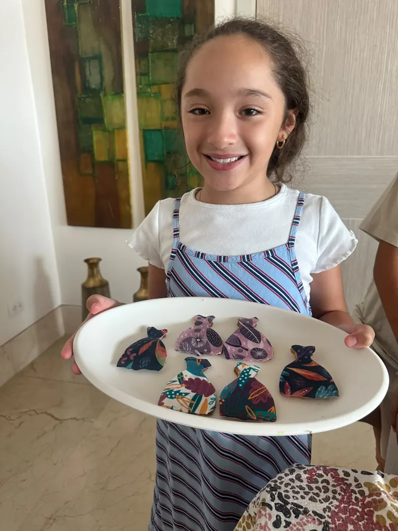 Niña sonriente mostrando galletas con forma de vestido hechas con la Quo-box Viste tu muñeca